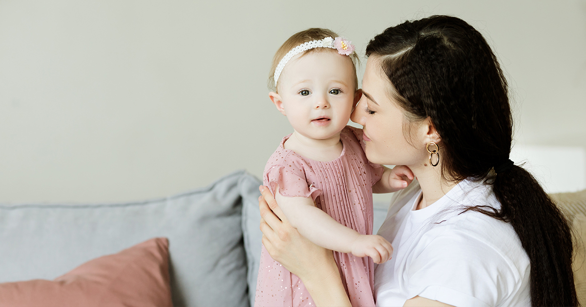 A mother holds her daughter as she looks towards the camera